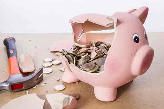 Broken piggy bank with hammer and money.