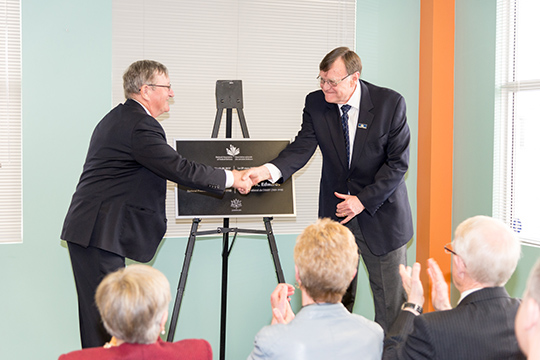 President Jean-Guy Soulière and Bob Edwards shake hands at the unveiling of the building dedication plaque.