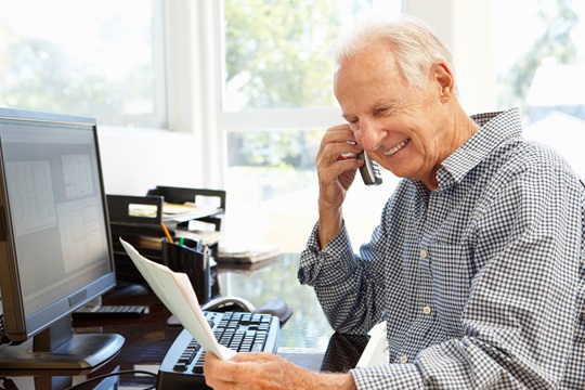 A man on a phone in front of desktop computer