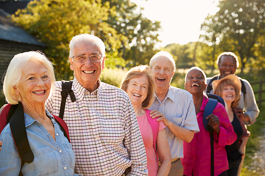 Un groupe de personnes âgées souriant à l'extérieur.