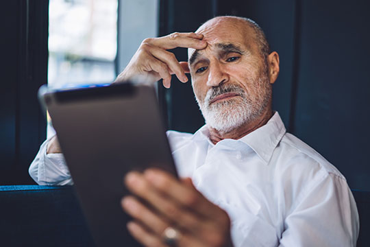 Restez informé sur les escroqueries COVID-19 Un homme qui lit une tablette.