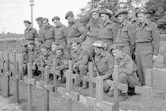 Members of the Royal Hamilton Light Infantry kneeling at the graves of comrades killed at Dieppe.