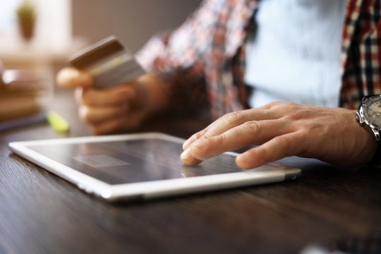 Adult man holding smartphone and credit card.