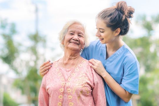 Proche aidant souriant en train de marcher avec un résident d’un établissement de soins de longue durée.