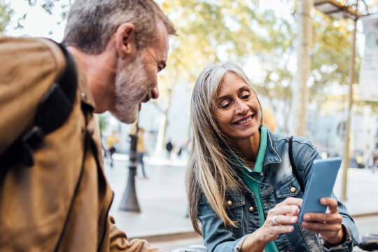 Adult couple outside, with smartphone.