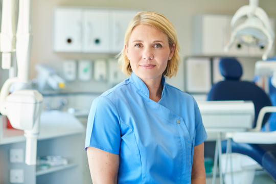 What is the Canadian Dental Care Plan? Adult dentist standing in her office.