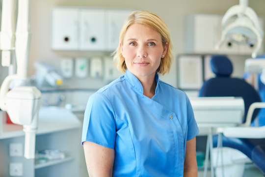 Adult dentist standing in her office.