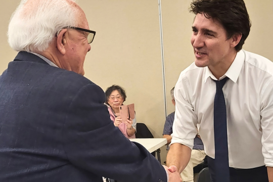 Federal Retirees volunteer Larry Duffield shakes hands with Prime Minister Justin Trudeau.