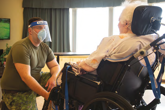 Soldat s'occupant d'une personne âgée en fauteuil roulant.