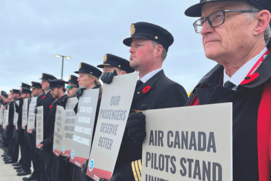 Air Canada pilots organized informational pickets Pilots in uniform are seen standing in a line and holding up placards.