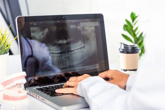 Taux de cotisations au RSDP pour 2025. Une dentiste visionne une radiographie orale sur un ordinateur portable.