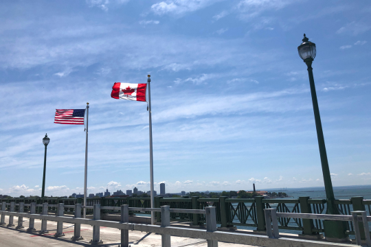 Déclaration de l’Association nationale des retraités fédéraux sur les tarifs douaniers américains. Drapeaux américain et canadien flottant dans le vent côte à côte, au Pont de la Paix.