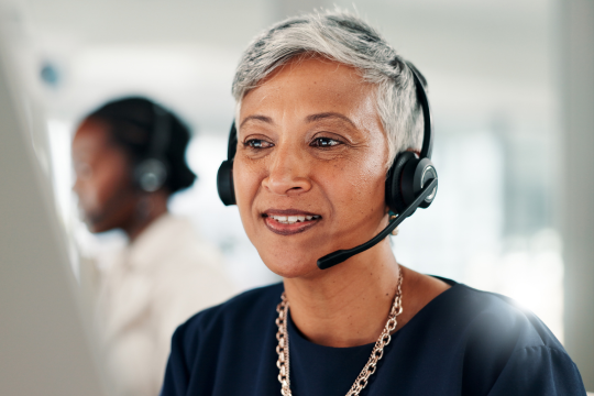Smiling woman speaking on headset to a client.