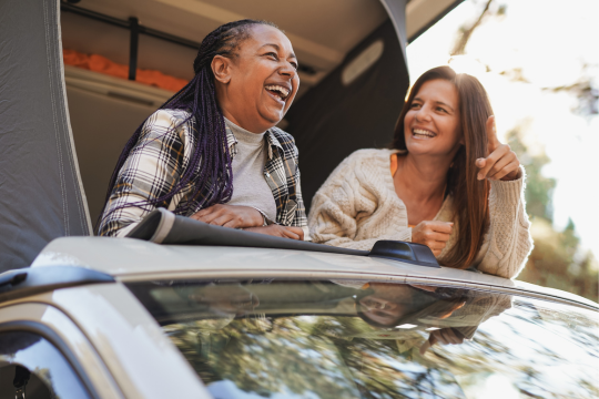 Deux femmes souriantes en voyage sur la route, dans une caravane-camping.