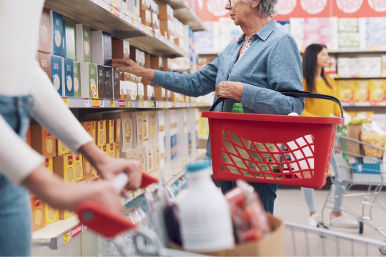 Une femme adulte magasine dans un supermarché, avec un panier.