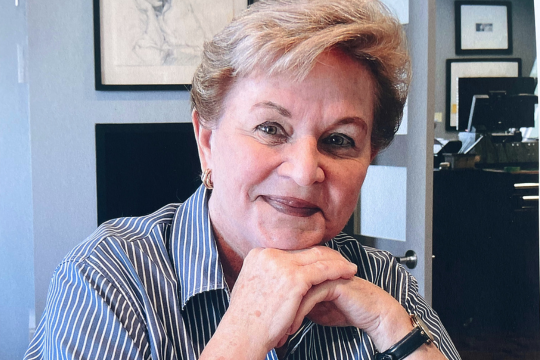 Marie-Paule is sitting and smiling at the camera