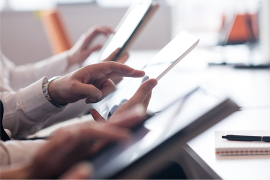 Close-up on team’s hands with tablets working at office desk.
