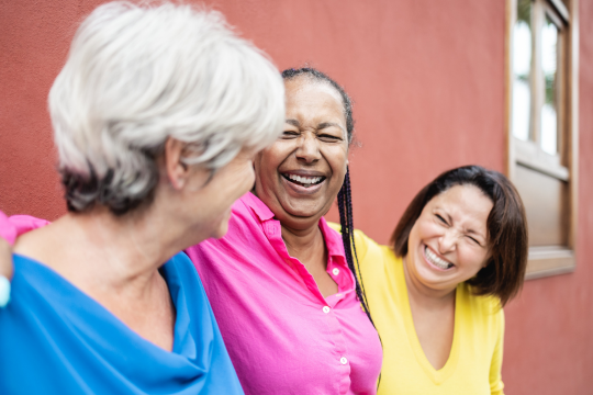 Three adult women friends standing together.