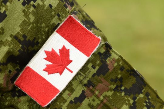 Camouflage military uniform with an embroidered Canadian flag.