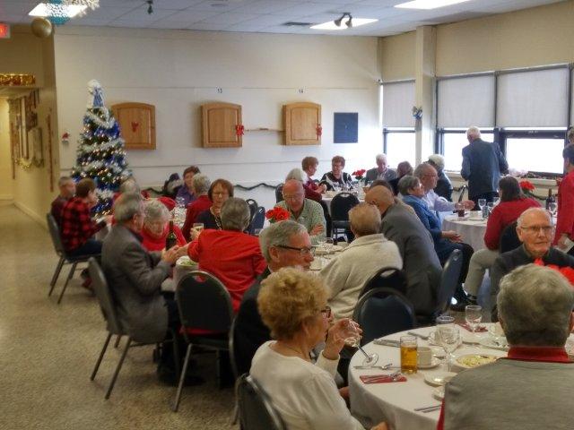 A group of people seated at round tables for a holiday banquet A group of people seated at round tables for a holiday banquet