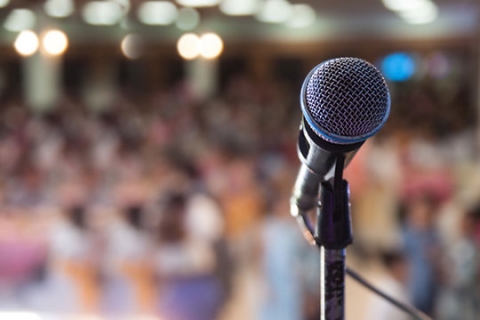 Un pied de microphone sur une scène devant un public. Un pied de microphone sur une scène devant un public.