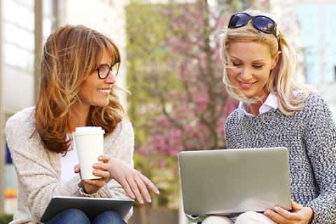 Businesswomen sitting at office park while using digital tablet and laptop Businesswomen sitting at office park while using digital tablet and laptop