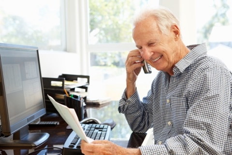 A man on a phone in front of desktop computer A man on a phone in front of desktop computer