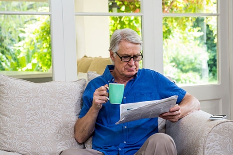 Un homme lit un journal tout en ayant le café dans le salon à la maison. Un homme lit un journal tout en ayant le café dans le salon à la maison.