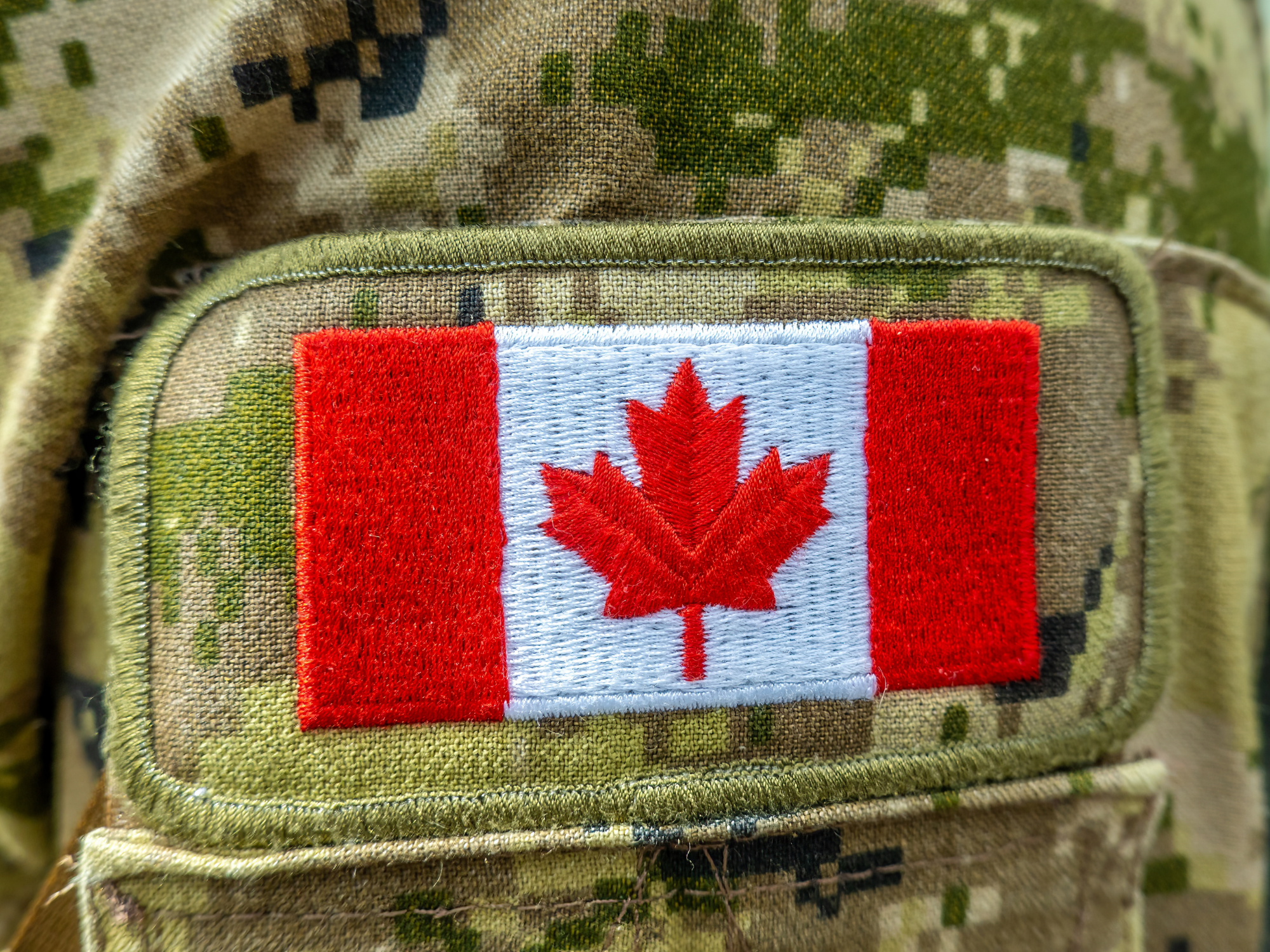 A Canadian flag patch on a military camouflage uniform.