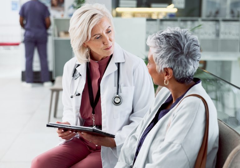 Doctor consulting with adult patient in hospital setting.