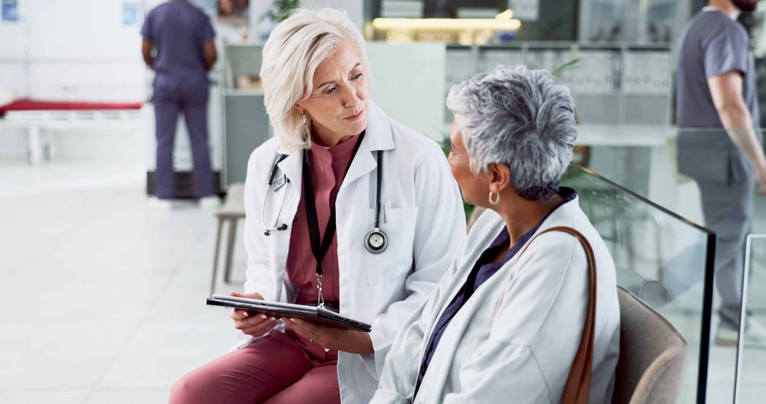 Doctor consulting with adult patient in hospital setting.