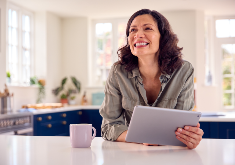 Smiling adult woman with tablet device.