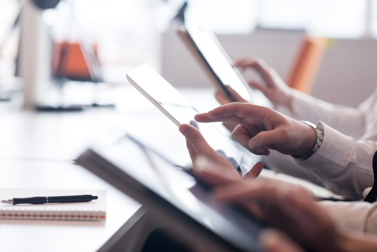 Close-up on team’s hands with tablets working at office desk.