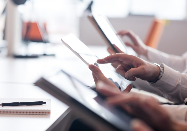 Close-up on team’s hands with tablets working at office desk.
