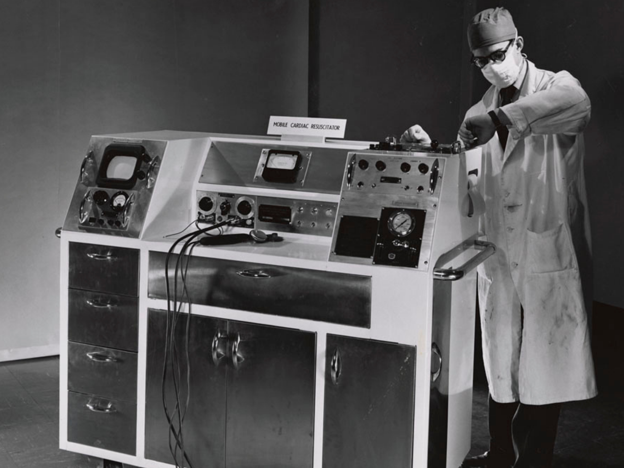 The Mobile Cardiac Resuscitator designed by Canadian engineer John Hopps. Alternate: Doctor examining x-ray image of chest with pacemaker implant.