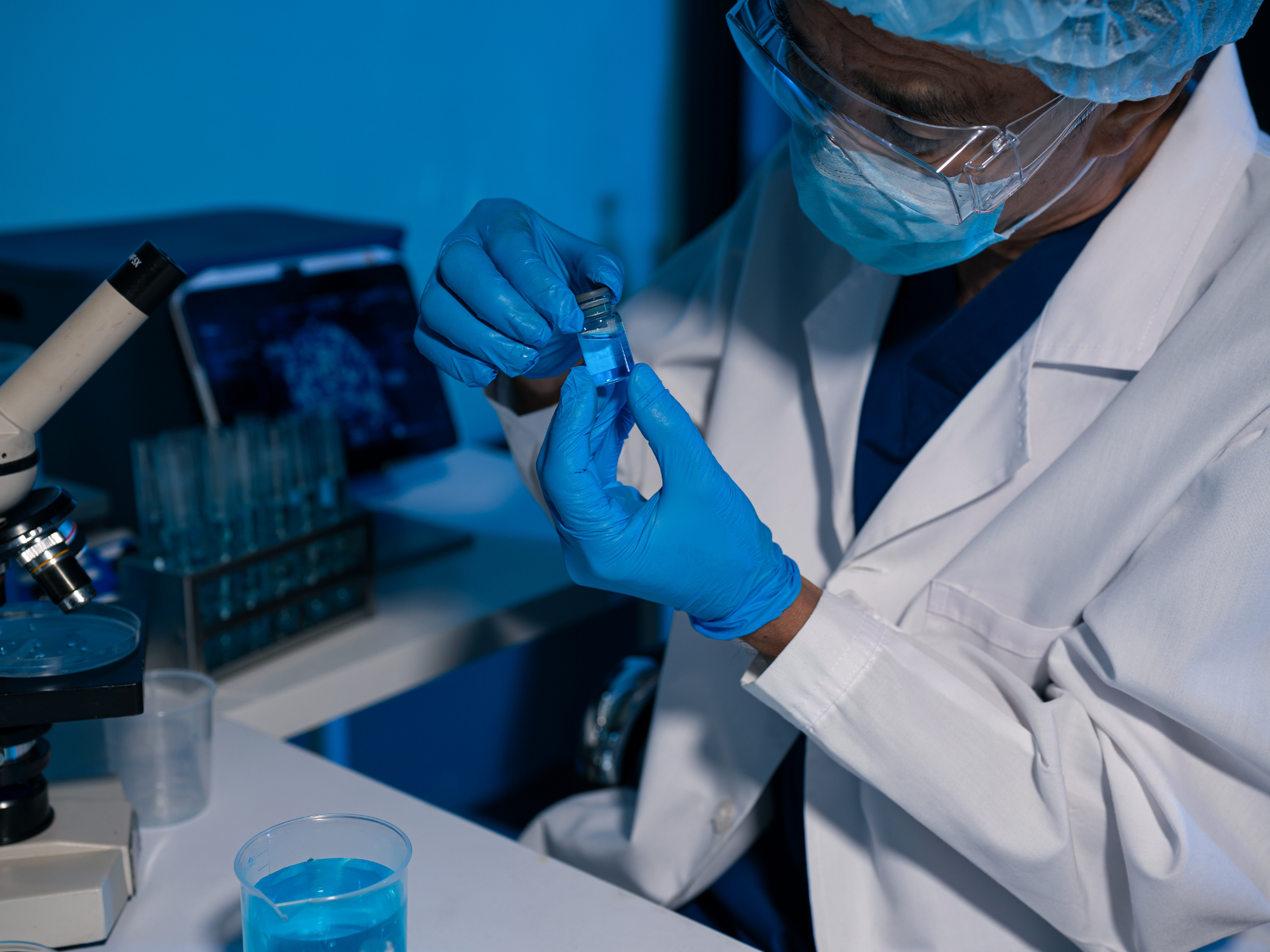 Chercheur portant un équipement de protection en laboratoire et examinant des échantillons liés à la recherche sur les maladies infectieuses.
